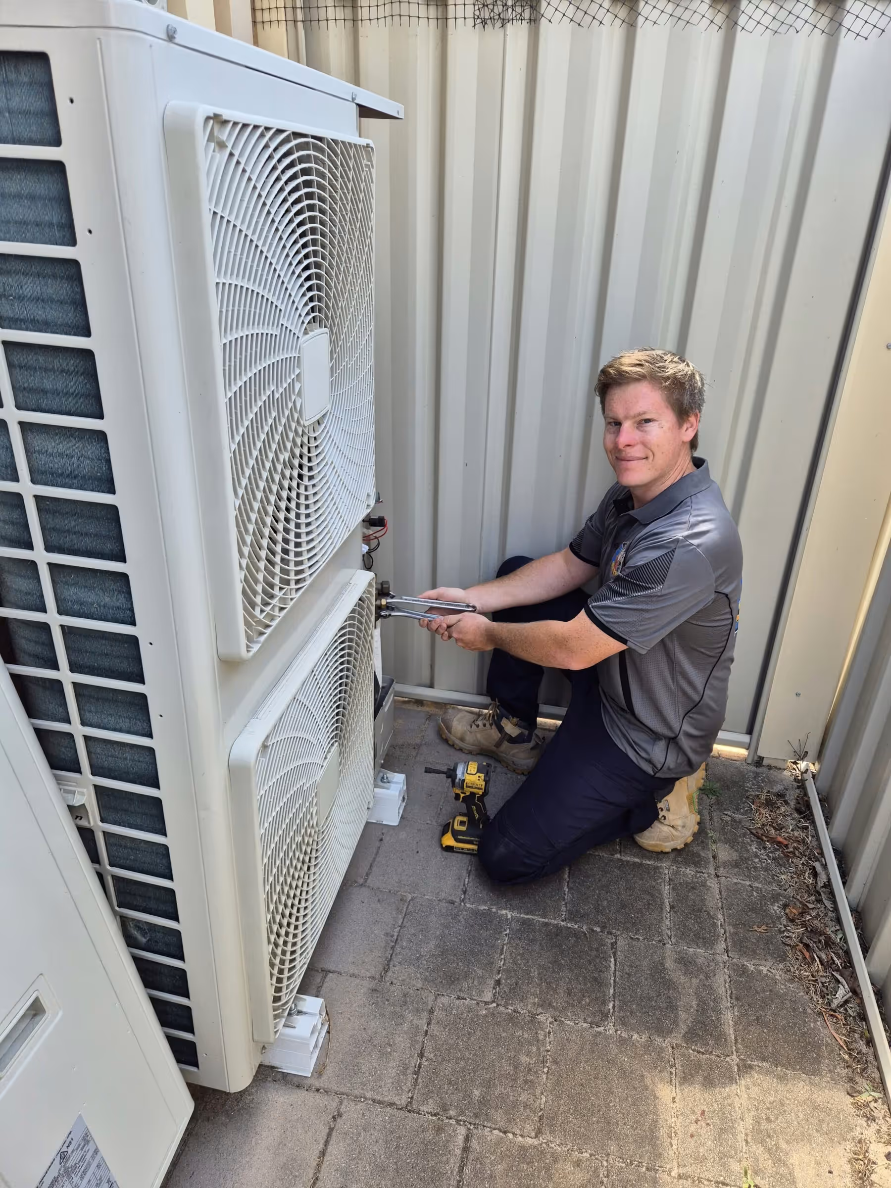 Technician servicing a multi-head outdoor air conditioning unit