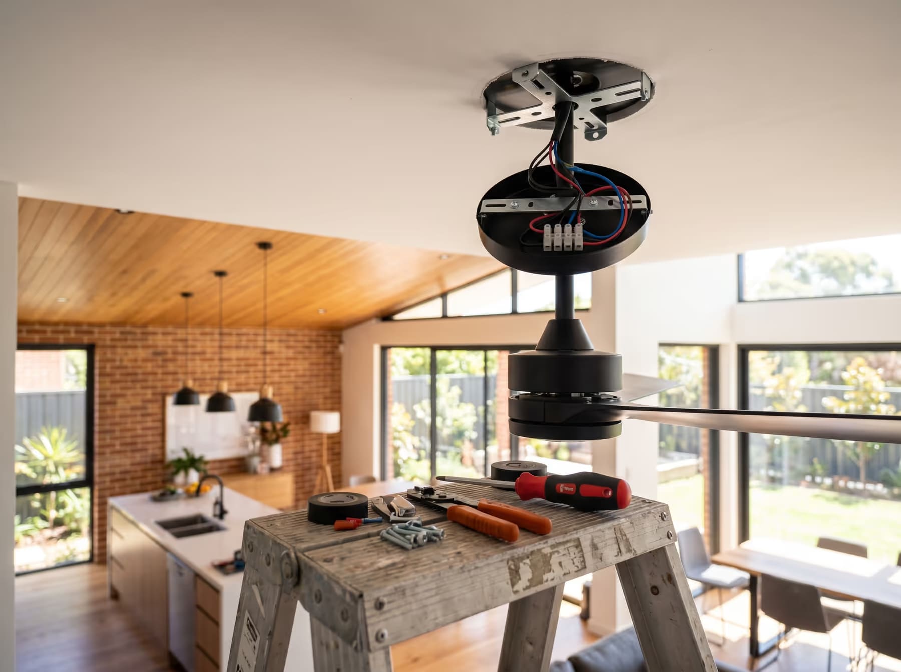 Ceiling fan being installed showing wiring and tools — Perth electrician service