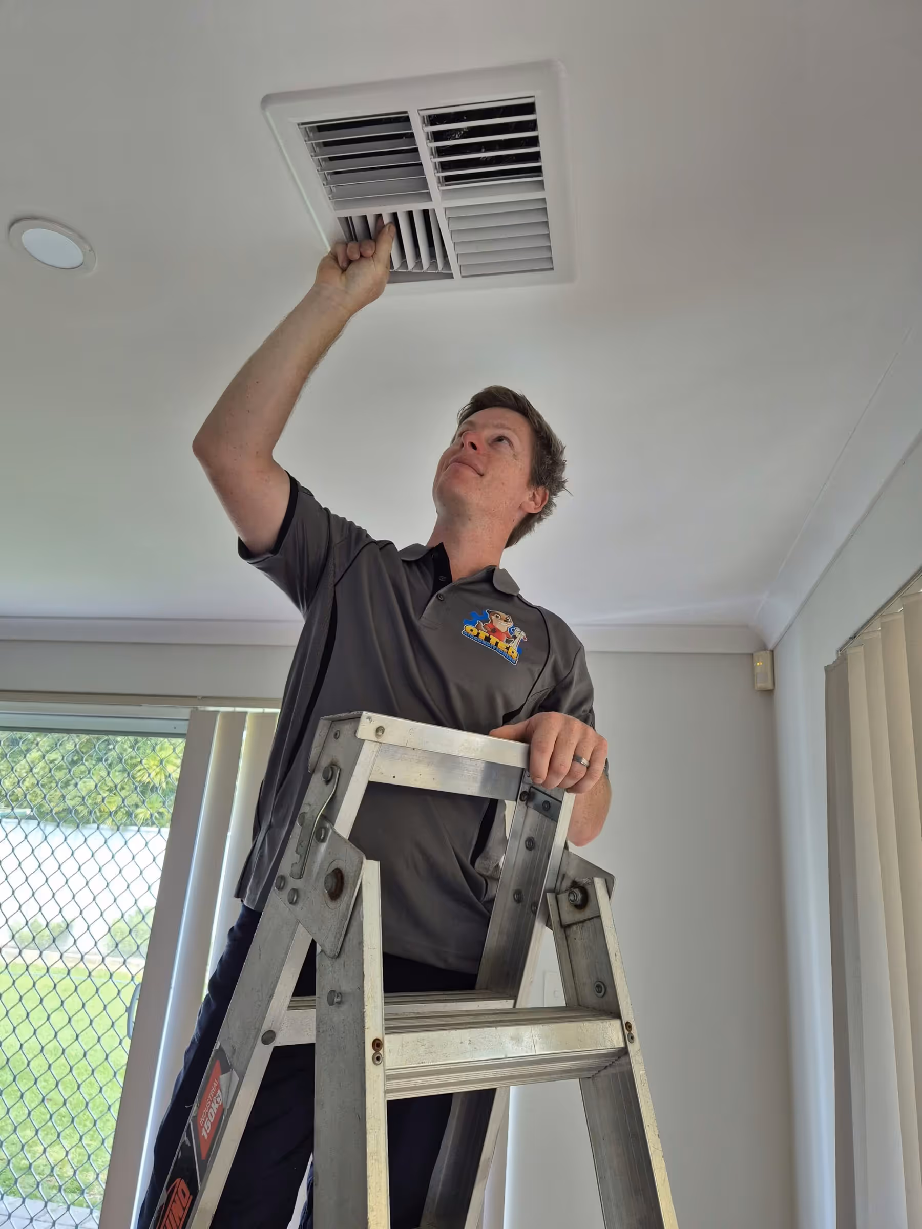 Technician adjusting a ducted air conditioning ceiling vent